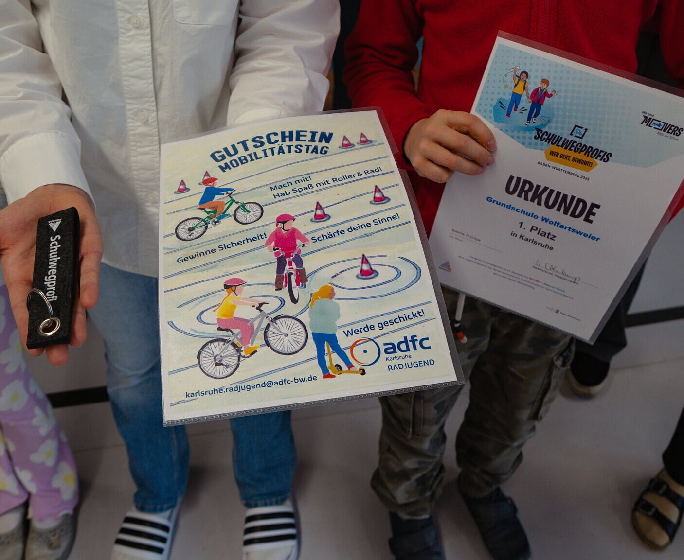 Grundschüler halten Ihren Gewinn, einen Schlüsselanhänger, eine Urkunde und den Gutschein für den Mobilitätstag  in den Händen