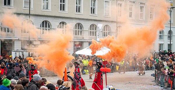 Zuschauer beim Umzug 2026 in der Innenstadt mit orangefarbenem Nebel durch den Narrenverein