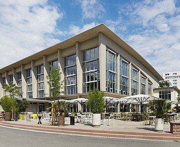 Blick auf die Südwestfassade mit großen Fenstern und einer Außenterrasse für Gäste.