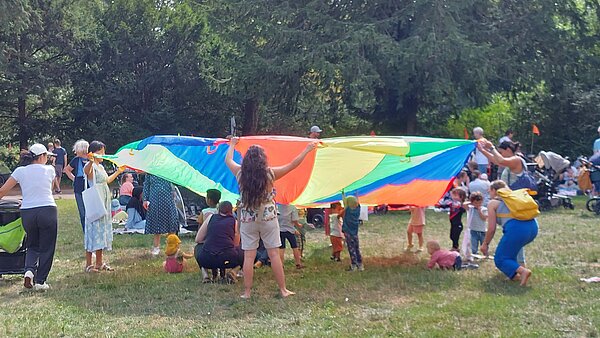Familien auf einer Wiese im Schlossgarten beim Spielen.