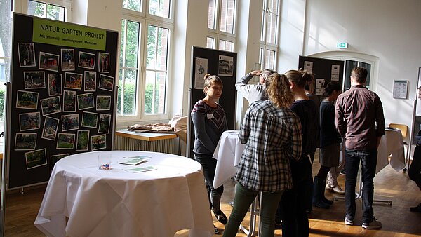 Personen, die an einem Stehtisch stehen und sich austauschen