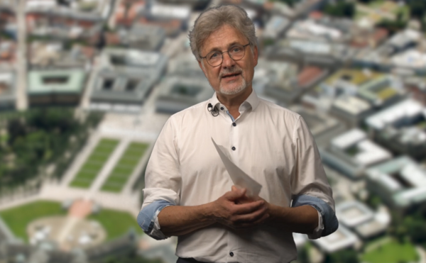 Oberbürgermeister Dr. Mentrup steht vor einer Luftaufnahme der Stadt Karlsruhe