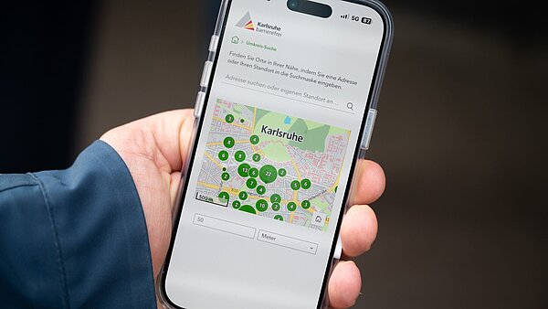 Hand hält Handy mit der Karlsruhe barrierefrei App in der Hand