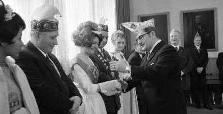 Bürgermeister Walther Wäldele mit Narrenkappe anlässlich der Begrüßung einer Delegation beim Händedruck mit einer jungen Frau.