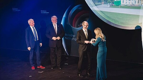 Nachhaltigkeitspreis 2015: Regina Halmich und Klaus Stapf bei der Preisübergabe mit den Vertretern der ebenfalls ausgezeichneten Städte Nürnberg und Recklinghausen im Hintergrund.