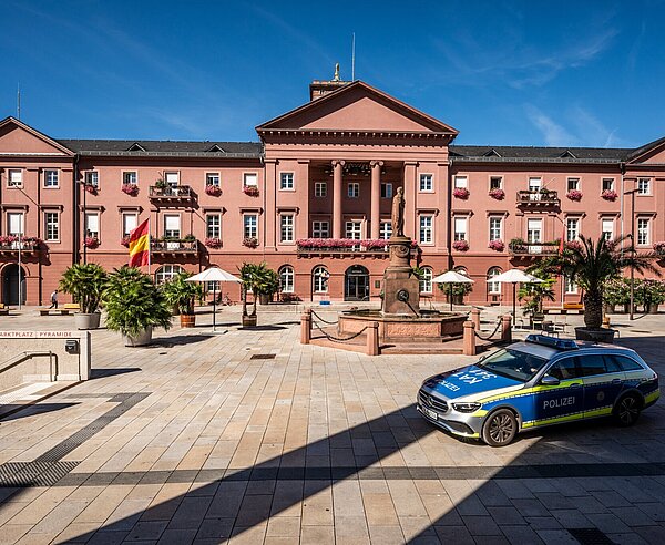 Außenansicht des Rathausgebäudes am Marktplatz in Karlsruhe mit Polizeiauto, das vorbeifährt