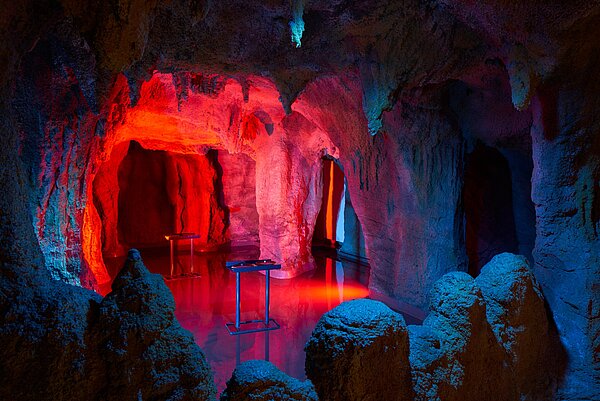 Zu Sehen ist eine Fledermaushöhle, erleuchtet von rotem Licht. 