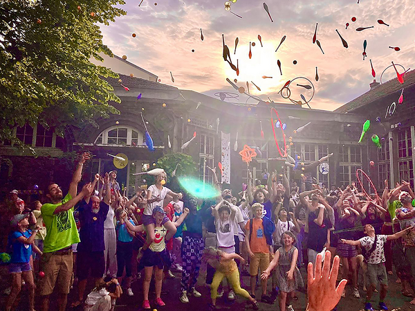 Kinder und Erwachsene mit jonglierenden Keulen in der Luft