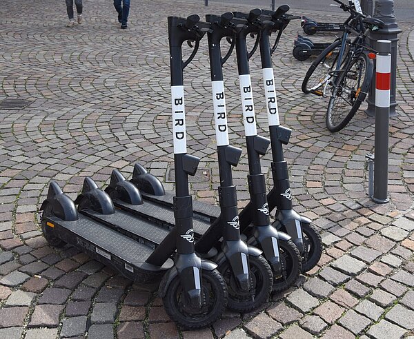 Vier Elektroroller parken nebeneinander. 