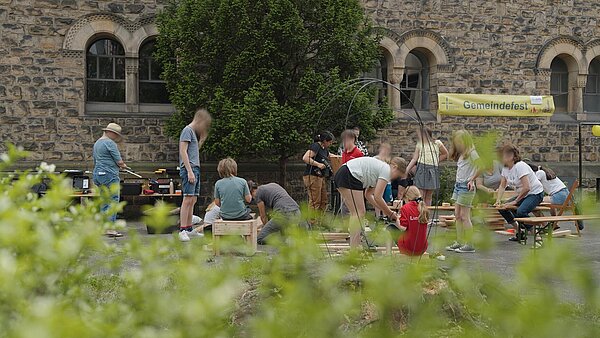 Grün im Vordergrund, Gruppe von Leuten, die Workshop machen, Kirche im Hintergrund