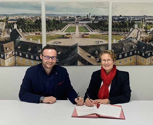 Pascal Rastetter (links) unterzeichnet im Beisein von Erster Bürgermeisterin Gabriele Luczak-Schwarz seinen Vertrag als neuer Geschäftsführer der KTG Karlsruhe Tourismus GmbH.
