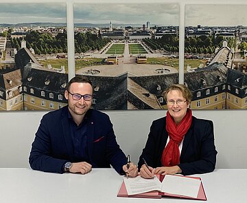 Pascal Rastetter (links) unterzeichnet im Beisein von Erster Bürgermeisterin Gabriele Luczak-Schwarz seinen Vertrag als neuer Geschäftsführer der KTG Karlsruhe Tourismus GmbH.
