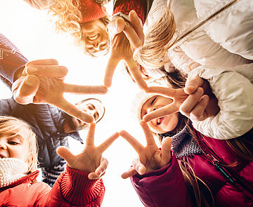 Familie von unten fotografiert, formen mit ihren Fingern einen Stern.