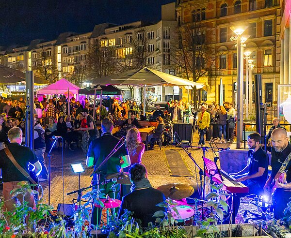 Feiernde und im Vordergrund eine aktive Band.