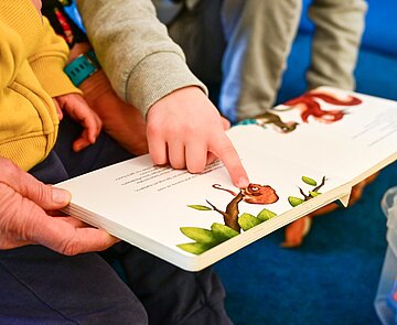 Kinder und Erzieher lesen gemeinsam ein Buch