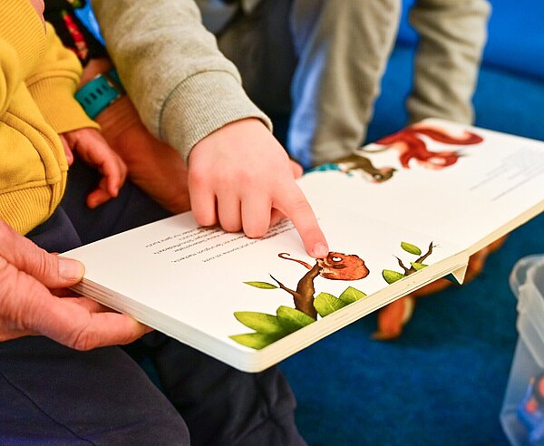 Kinder und Erzieher lesen gemeinsam ein Buch