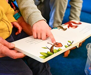 Kinder und Erzieher lesen gemeinsam ein Buch