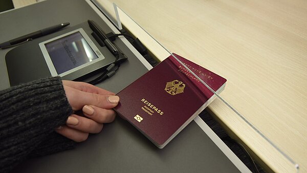 Händische Übergabe eines beantragten Reisepasses im Bürgerbüro