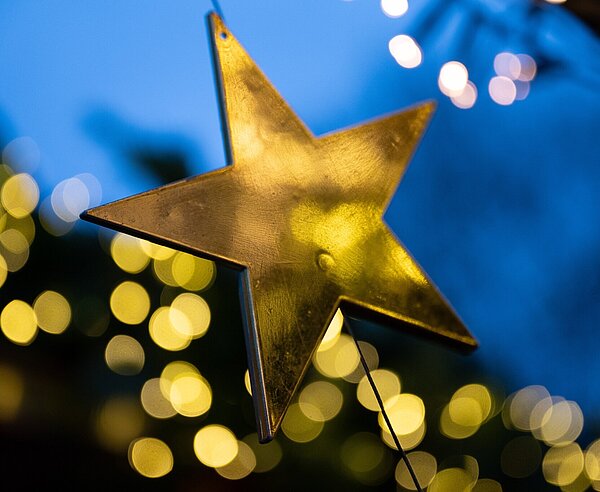 Goldener Stern vor unscharfen Lichtern am Abend