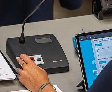 Gemeinderatsfraktionen und Bürgermeisterbank während der Gemeinderatssizung , Hand drückt Knopf bei Abstimmung