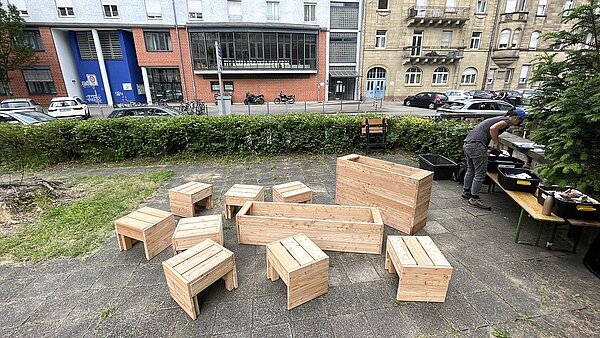 Mehrere Hocker und Hochbeete auf dem Kirchplatz