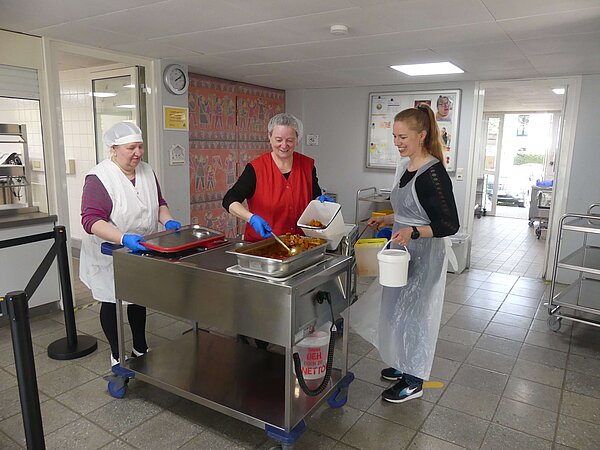 Drei Frauen stehen in der Kantinen Küche der Ernst-Reuter-Schule und packen Speisereste für Foodsharing ein.