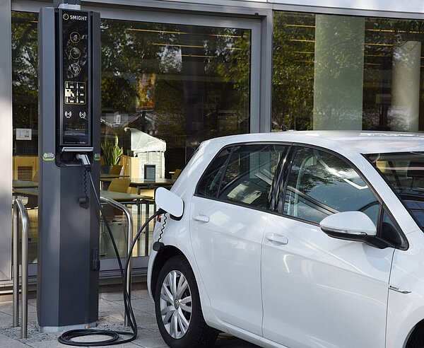 Ein weißes Elektroauto lädt an einer Ladestation.