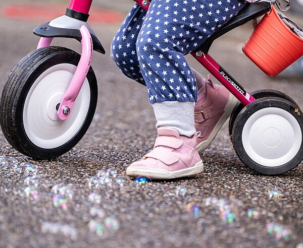 Kind mit Dreirad steht auf Straße