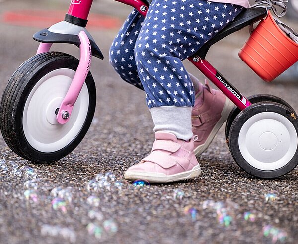 Kind mit Dreirad steht auf Straße