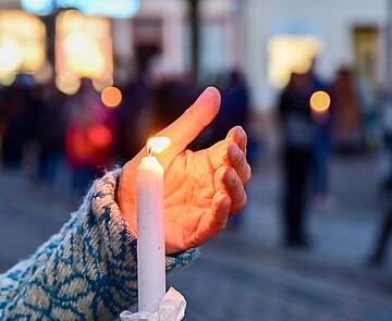 Bei der Mahnwache "Karlsruhe steht zusammen: Solidarität mit der Ukraine!" am 6. März auf dem Marktplatz wird eine brennende Kerze hochgehalten.
