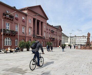 Marktplatz mit Rathaus mit Blick Richtung Norden bei gutem Wetter mit Personen und Radfahrer