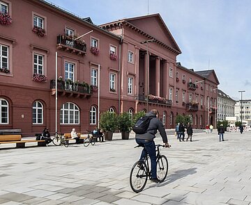 Marktplatz mit Rathaus mit Blick Richtung Norden bei gutem Wetter mit Personen und Radfahrer
