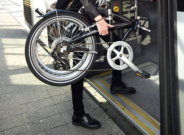 Das Foto zeigt einen Fahrgast mit Fahrrad beim Einstieg in einen Bus.  