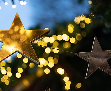 Goldene Sterne vor unscharfen Lichtern am Abend