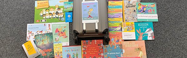 Kinderrechtekoffer vor dem alle enthaltenen Materialien ausgebreitet sind