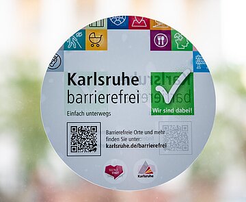 Aufkleber an der Eingangstür vom Rathaus weist auf die Barrierefreiheit und Barrierefreie Orte in Karlsruhe hin.