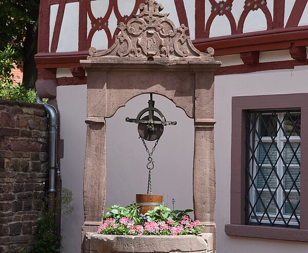 Alter Sandsteinbrunnen vor Fachwerkhaus.