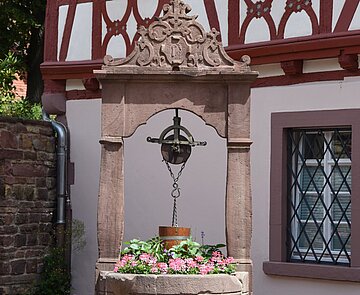 Alter Sandsteinbrunnen vor Fachwerkhaus.