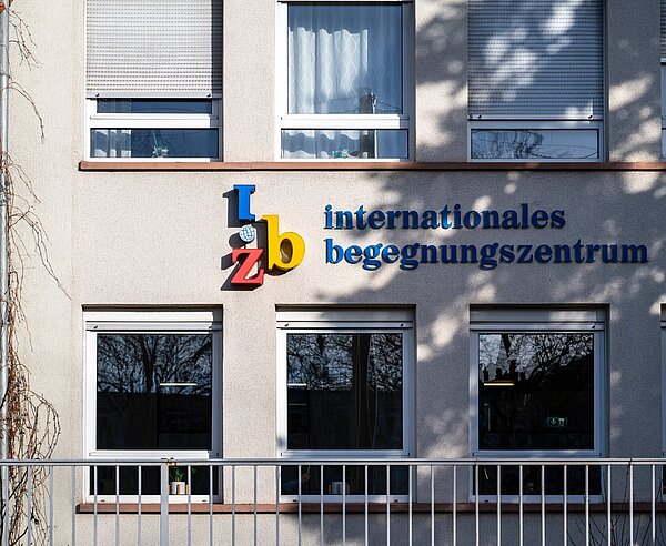 Schriftzug "internationales begegnungszentrum" auf einer schattigen Häuserwand.