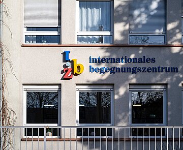 Schriftzug "internationales begegnungszentrum" auf einer schattigen Häuserwand.