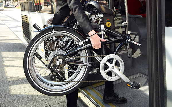 Das Foto zeigt einen Fahrgast, der ein Fahrrad mit in den Bus nimmt.
