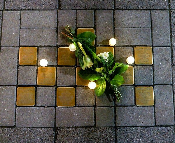 Blumen- und Kerzenschmuck auf den Stolpersteinen vor der Stadtbibliothek anlässlich des Holocaust-Gedenktags am 27. Januar 