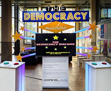 Stand einer Ausstellung mit Schriftzug "Democracy Machine"
