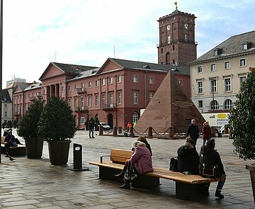 Marktplatz mit besetzten Bänken, im Hintergrund Pyramide und Rathaus