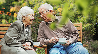 Älteres Ehepaar trinkt Kaffee im Garten