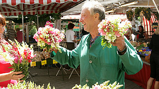 Das Bild zeigt einen Marktstand mit Blumen und steht symbolisch für den Wochenmarkt Rüppurr.