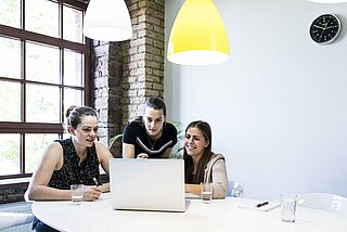 Drei Studentinnen arbeiten im Team an einem Laptop.