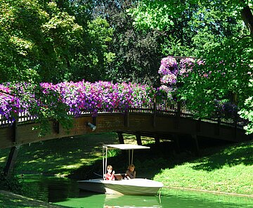 Das Bild zeigt eine Brücke über dem Stadtgartensee mit einer Gondoletta im Zoologischen Stadtgarten. 