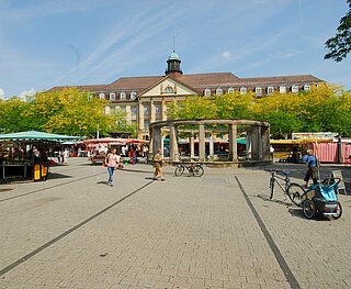 Auf dem Stephansplatz stehen Marktstände, laufen Fußgänger und fährt ein Radfahrer mit Anhänger.