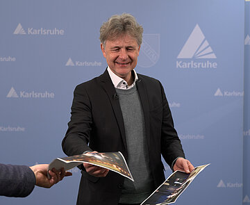 Oberbürgermeister Dr. Mentrup steht vor einer blauen Wand